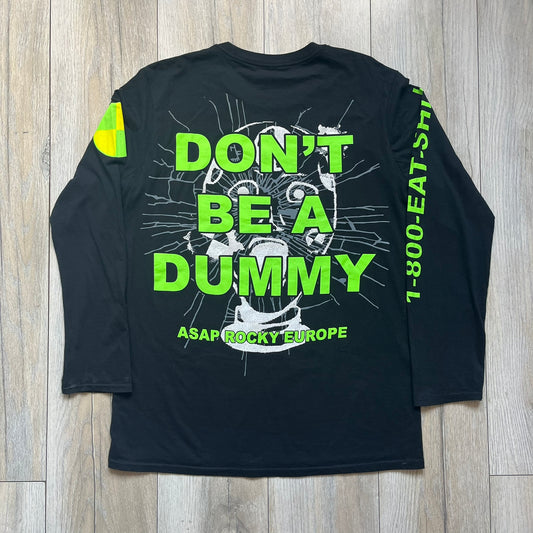 A$AP Rocky 2019 “Injured Generation” Tour “Pickpockets” Longsleeve is a black long-sleeve T-shirt released as part of the Injured Generation tour merchandise collection. The front features a large graphic of A$AP Rocky with green “Warning! Beware of Pickpockets” text. One sleeve includes “1-800-EAT-SHIT” text, while the other features a yellow and green testing-style logo. The back displays large green “Don’t Be a Dummy A$AP Rocky Europe” text layered over a white dummy mask graphic. Made in the USA.