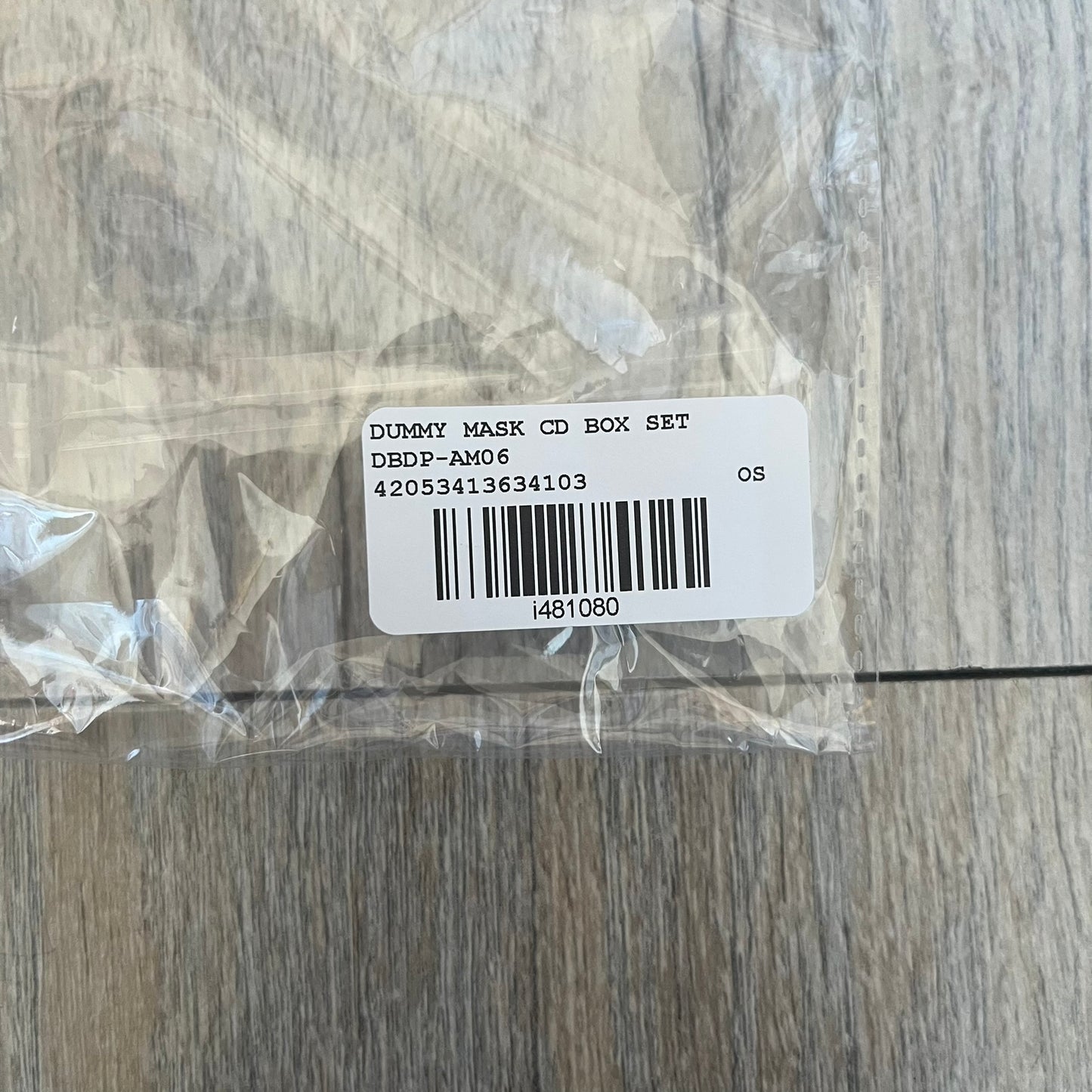 A$AP Rocky “Don’t Be Dumb” Dummy Mask is a limited release item from the AWGE website tied to the rollout of Don’t Be Dumb by A$AP Rocky. The beige mask features printed graphics including “DBD” on the forehead, a stitched scar detail on one side, and yellow crossed-out circle eyes made from mesh for visibility. The mouth area includes a stop sign graphic with “Snitchin” text below, referencing a track from the album.