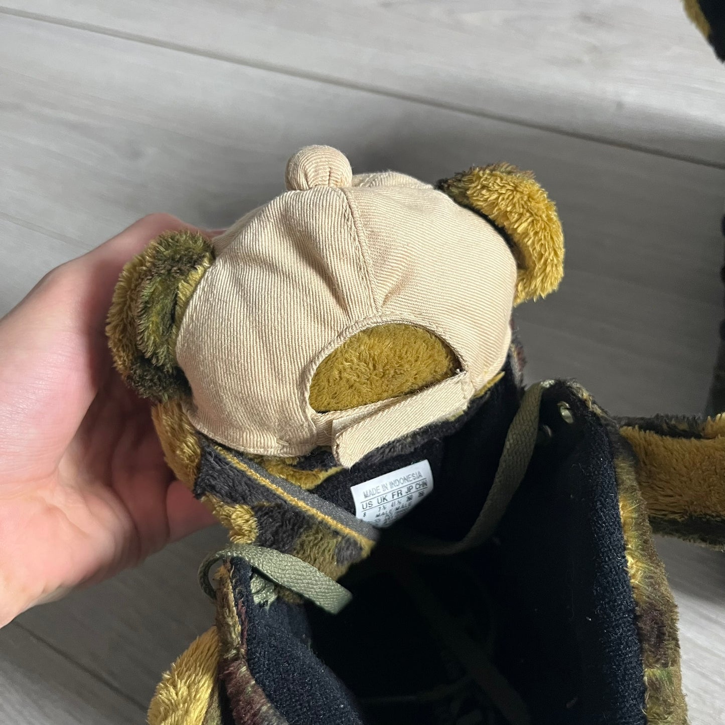 Adidas Jeremy Scott “Camo Bear” Sneakers (Style Q20917) released on March 16, 2013, in Earth Green/Black/Shioli. Featuring plush fleece uppers with a camouflage pattern, black three stripes, and a fully stuffed teddy bear head and arms on the tongue. Includes Jeremy Scott signature detailing on the inside heel and a black rubber sole.