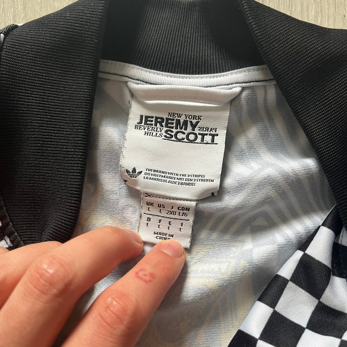 Close-up of a label on a garment with 'Jeremy Scott' branding.