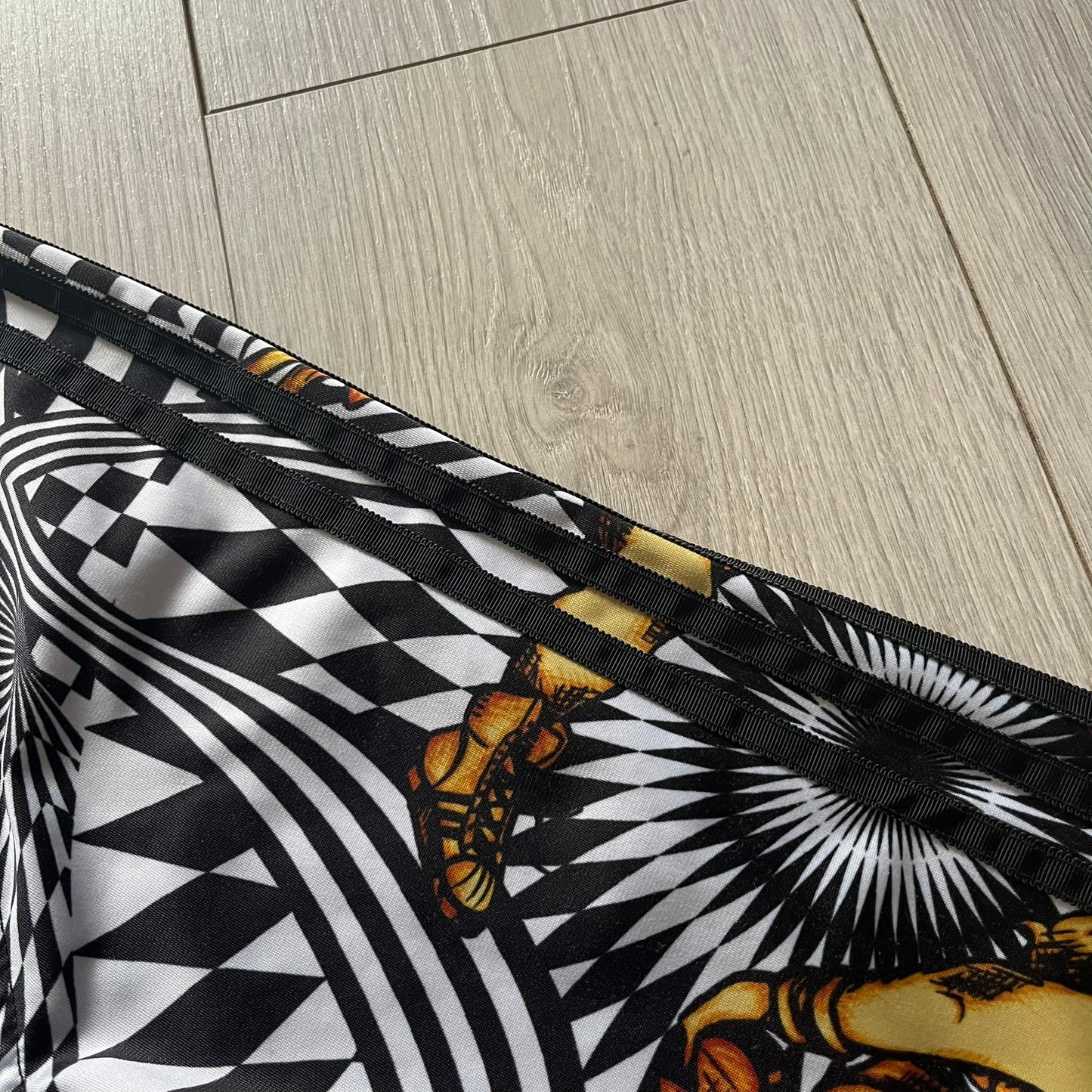 Close-up of a black and white patterned fabric with butterfly design on a wooden floor.