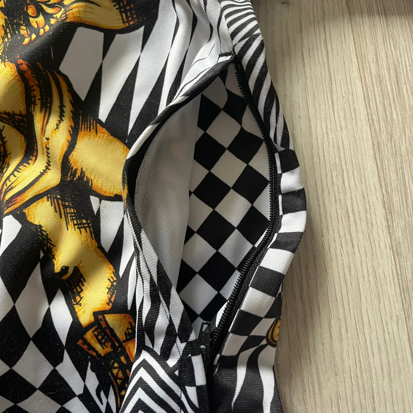 Black and white checkered jacket with yellow pattern on a wooden surface