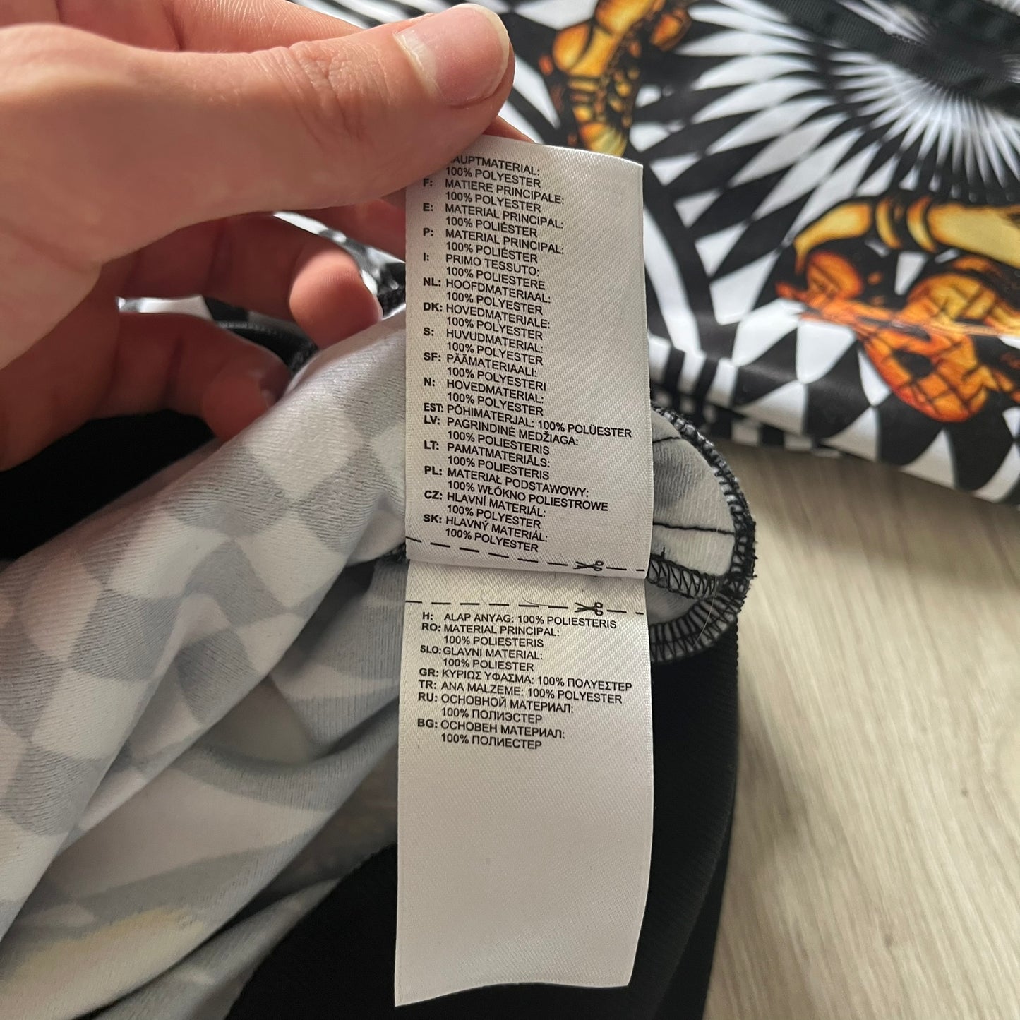 Close-up of a fabric label held by a hand with a patterned background