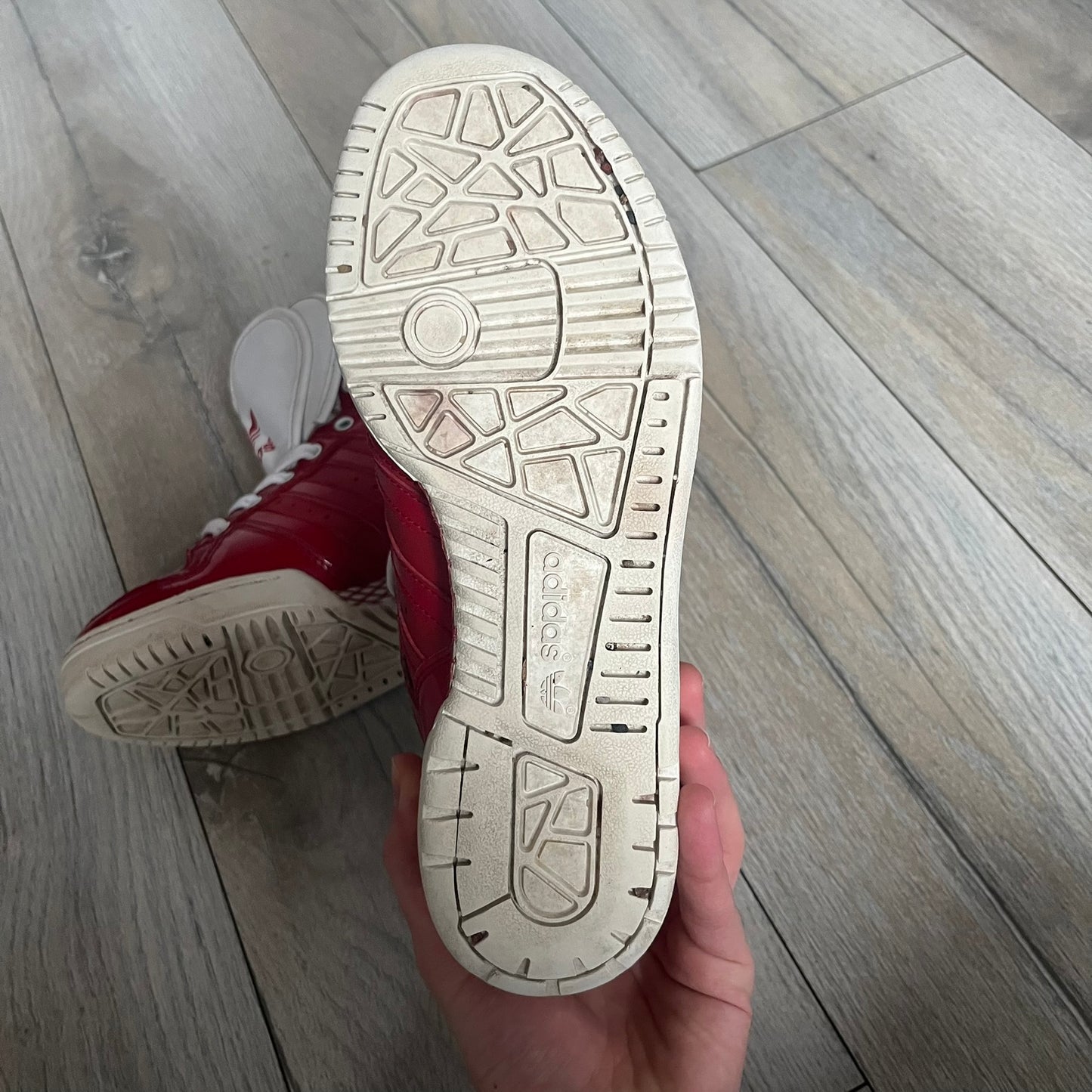 Adidas Originals Metro Attitude Logo Heart Sneakers are women’s sneakers released in 2012, featuring a red suede upper with matching University-Red accents. The design includes dual heart-shaped tongues in white with red Adidas logos, paired with a white sole and laces. Metro Attitude Logo Heart W model (G61014) inspired by Jeremy Scott collaborations.