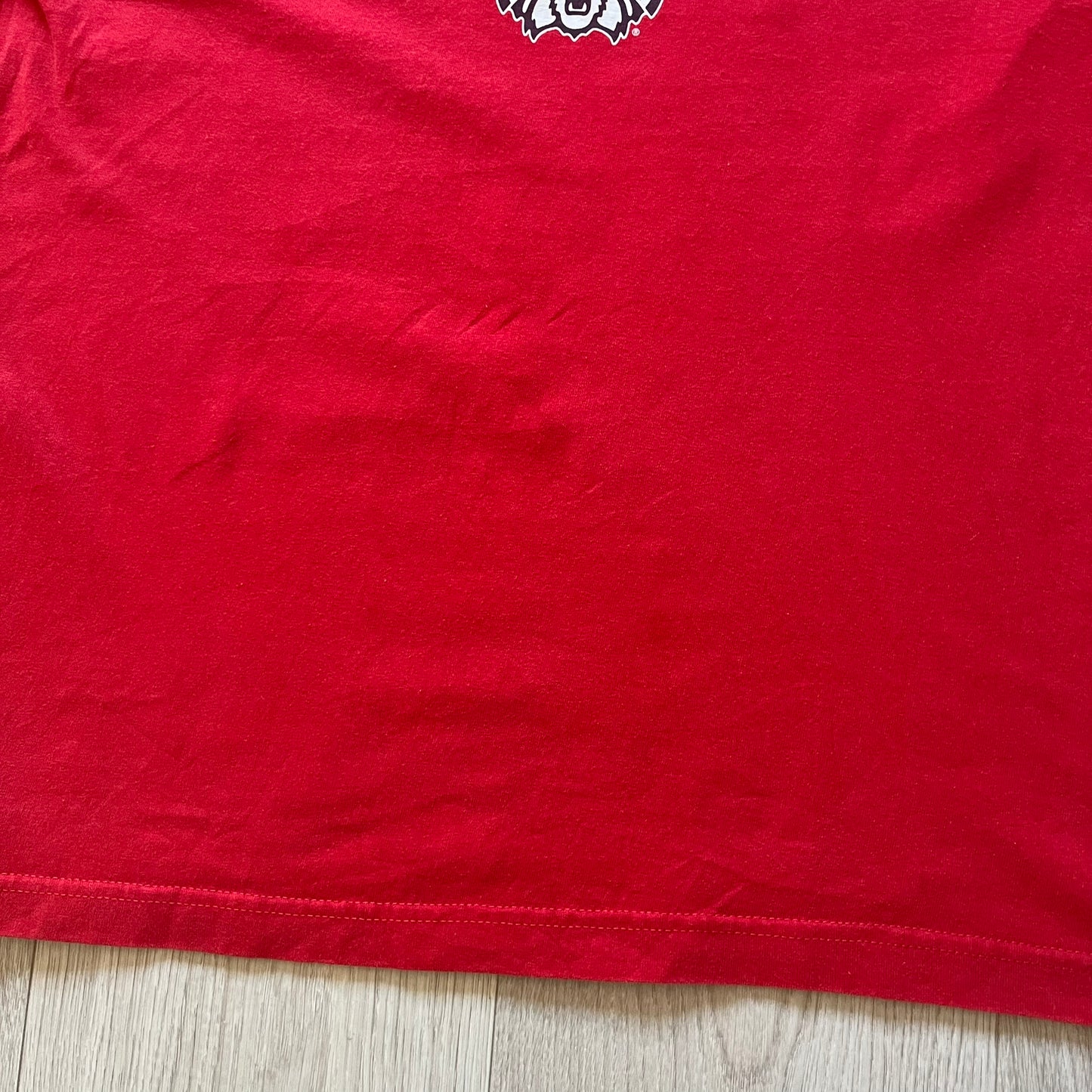 Red t-shirt with a logo on a wooden surface