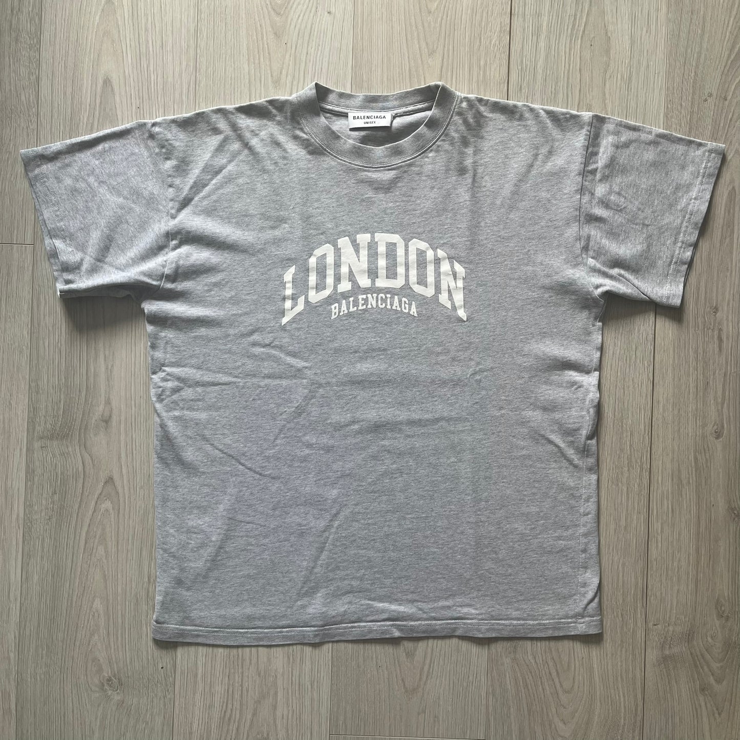 Gray t-shirt with 'London Balenciaga' text on a wooden surface