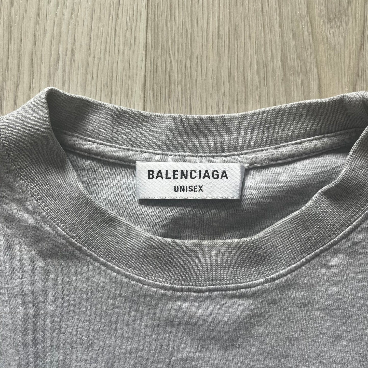 Gray t-shirt with Balenciaga label on a wooden surface