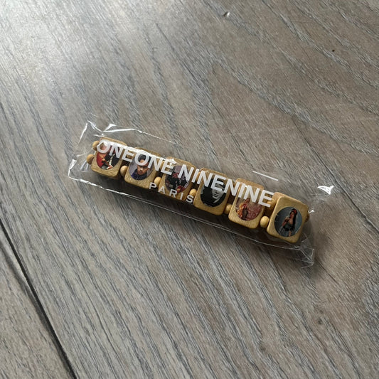 Beige “Forever 27 Club” bracelet by Bazo 1199, showcasing painted wooden beads and engraved portraits of legendary artists from the infamous 27 Club like Kurt Cobain, Basquiat, and Fredo Santana. Signed “forever 27 club” and “1199” on the inside.