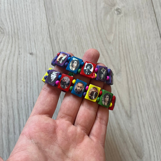 Multicolor “Forever 27” bracelet by Bazo 1199, showcasing painted wooden beads and engraved portraits of legendary artists from the infamous 27 Club like Kurt Cobain, Basquiat, and Fredo Santana. Signed “forever 27” and “1199” on the inside, this piece is a striking nod to music and art history. Limited and highly sought-after, it captures both style and cultural significance.