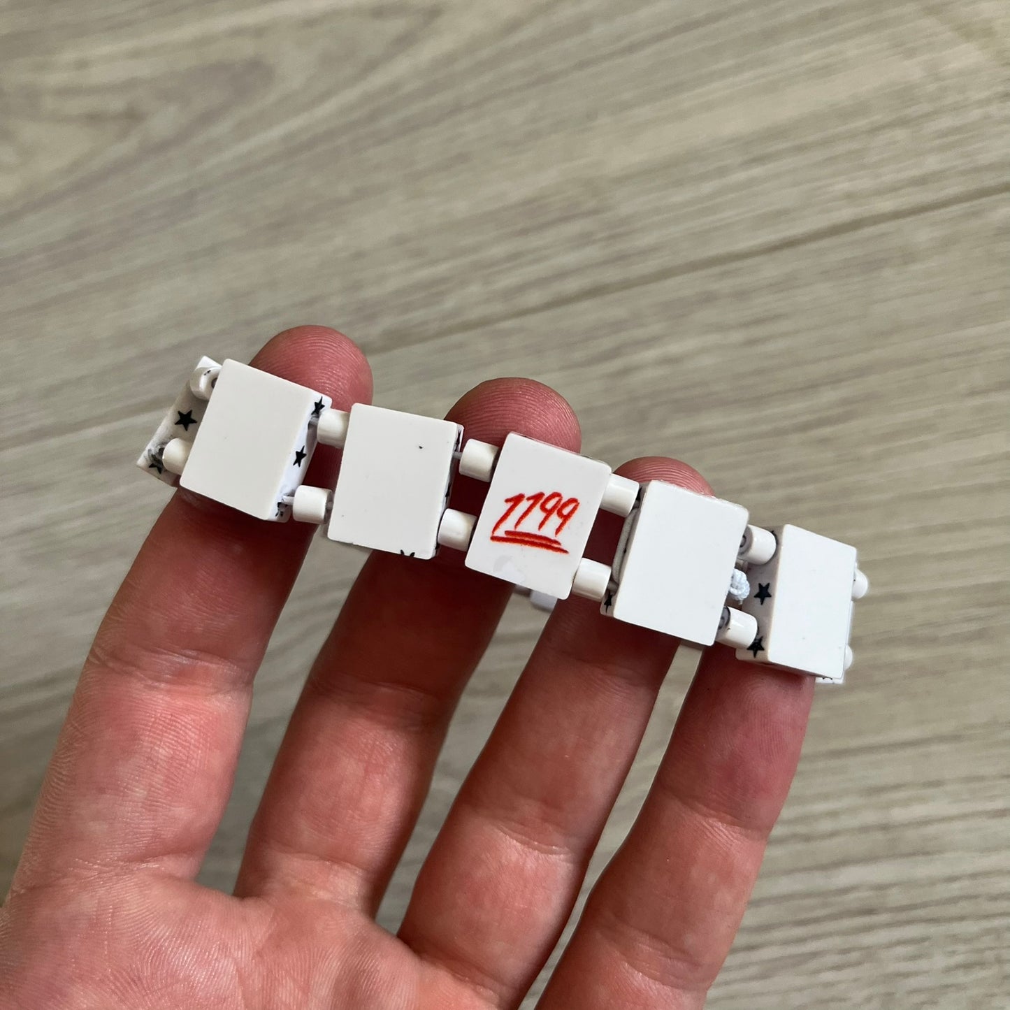 Bazo 1199 “White on Black” Stars Bracelet is a acetate bead bracelet featuring white beads with black star graphics printed on the tops and sides. One bead is marked with a red 1199 logo on the inside. It comes with the original foil packaging.