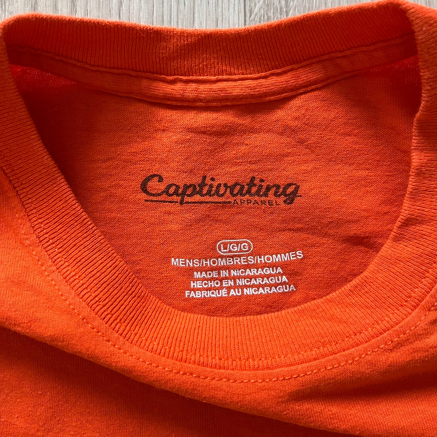 Close-up of an orange shirt with 'Captivating Apparel' branding on the label.