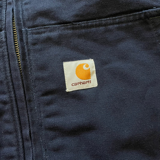 Carhartt Armstrong Full Swing Active Jacket in navy, crafted from heavyweight 12-ounce fleece-lined cotton duck for warmth and durability. Designed with stretch panels across the back and elbows, it allows full range of motion while maintaining a broken-in, comfortable fit. Features include a fleece-lined adjustable hood, rib-knit storm cuffs and waist, triple-stitched main seams, and multiple secure pockets, making it a trusted workwear piece with modernized functionality.