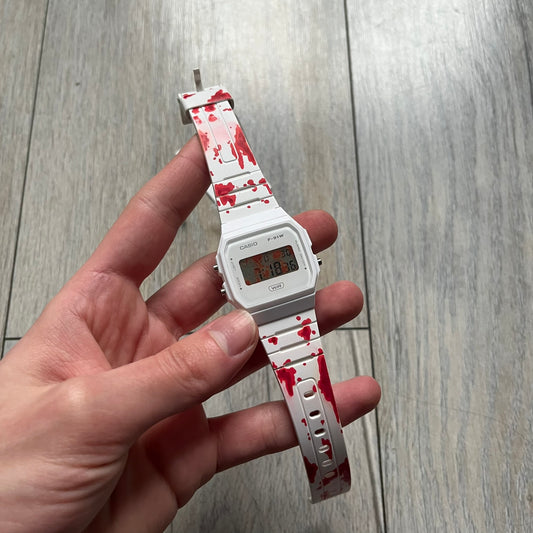 Custom Casio F-91W White digital watch featuring a Bloody filter screen and custom painted straps. Slim 8.5 mm profile, lightweight 21 g build and flexible bio-based resin band ensure lasting comfort. Includes alarm, stopwatch, and microlight function for everyday functionality.
This watch is a 1/1 sample. The paint on the straps is not holding perfectly as with more force it can be smudged. For the best effect we reccomend covering it with a special paint or spray to make it 100% last. 