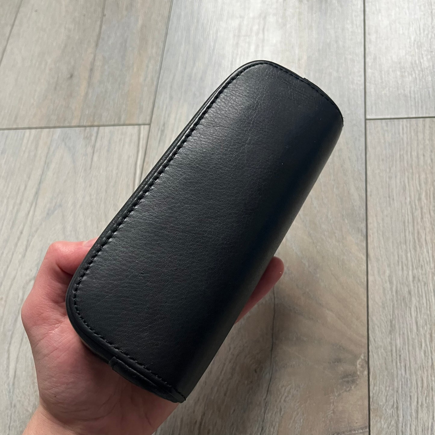 The Chrome Hearts Black Leather Sunglasses Case is a black leather zip case with a Chrome Hearts logo on the front, flanked by two cross motifs. It features a CH dagger zipper pull made from black plastic and metal. The interior is monogrammed with vine dagger logos and includes an attached soft inner compartment designed to hold a cleaning cloth.