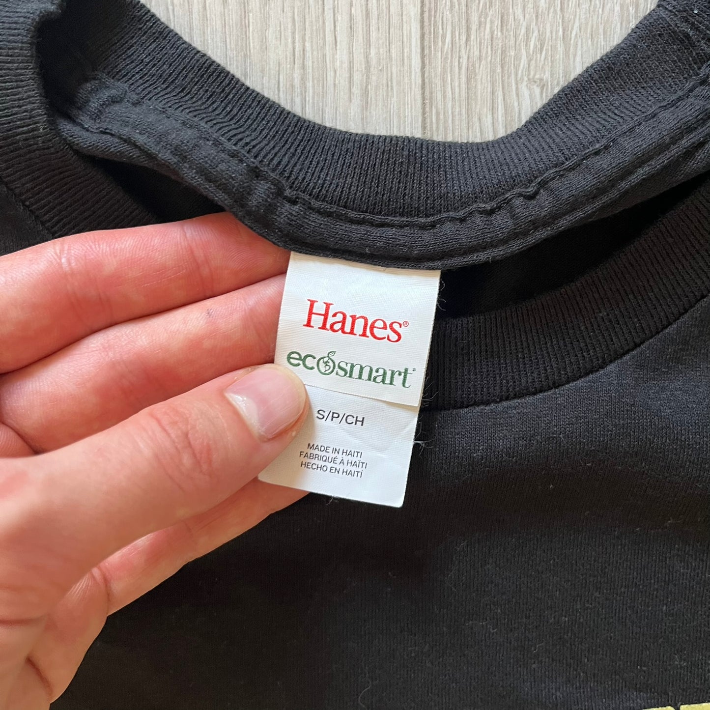 Hanes ecosmart tag on a black shirt with a hand holding it.