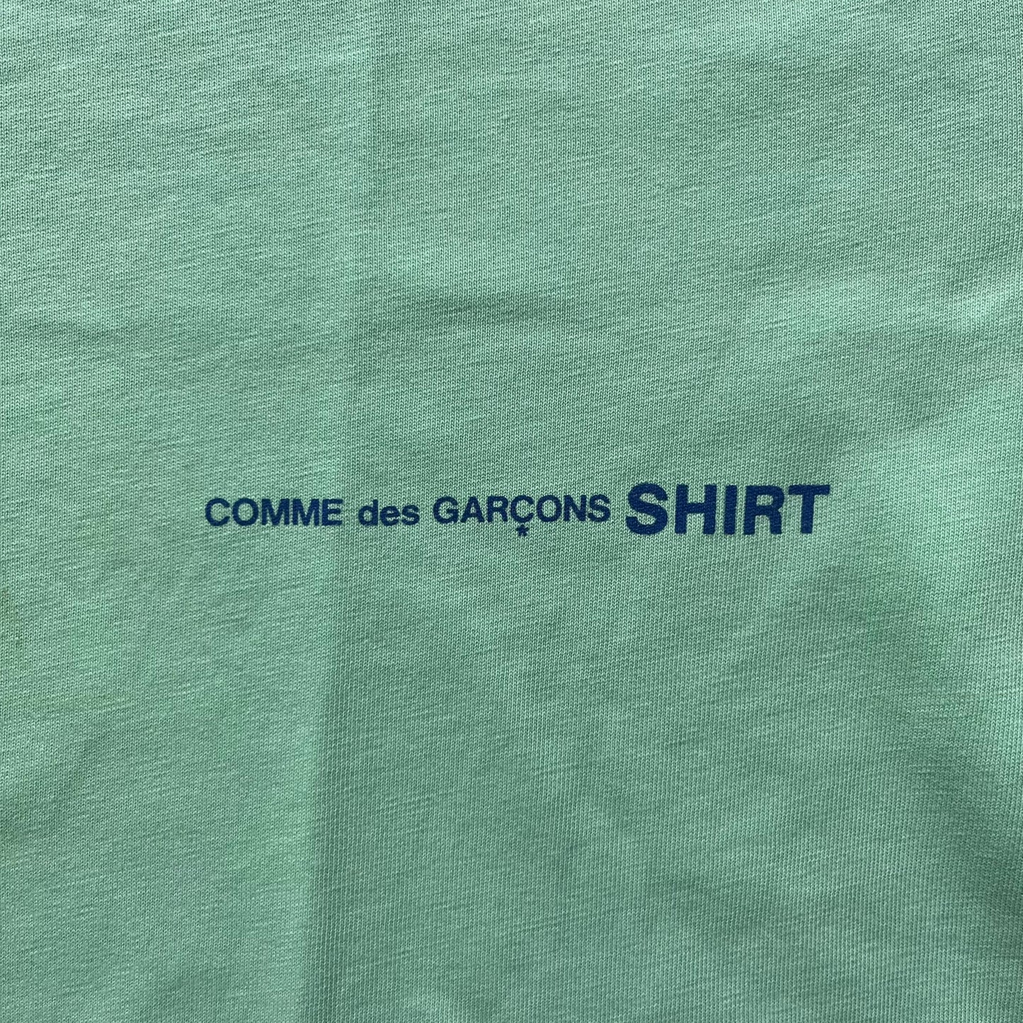 Green shirt with 'COMME des GARÇONS SHIRT' text in blue.