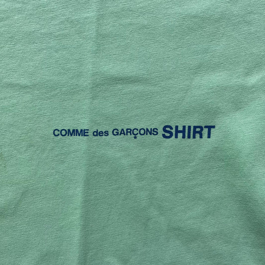 Green shirt with 'COMME des GARÇONS SHIRT' text in blue.