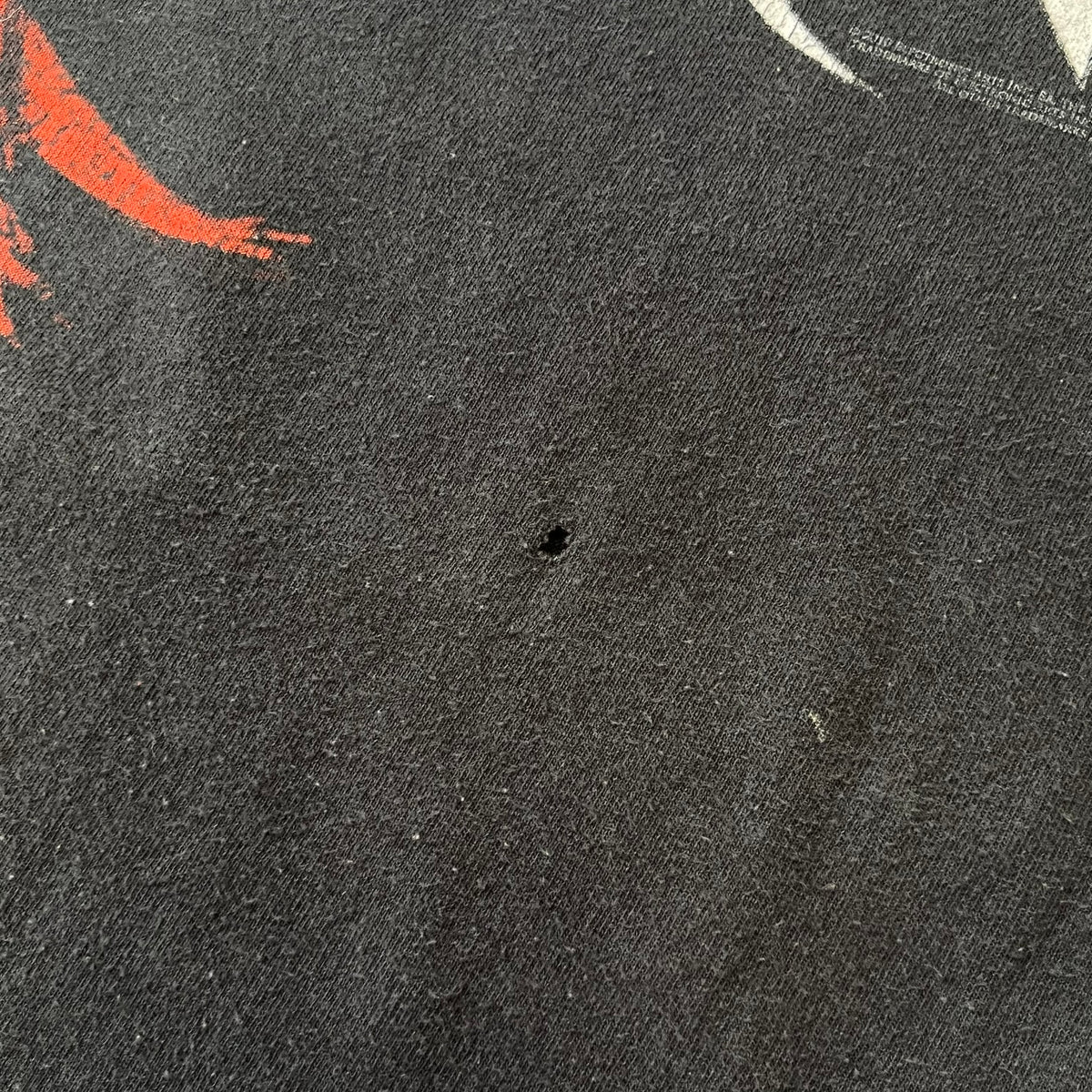 Dante's Inferno 2010 Black Promo Tee features a black construction made on an Anvil blank. The front has the Dante's Inferno game logo with a cross graphic on the left, featuring a red fabric-like detail, with small white licensing text underneath.