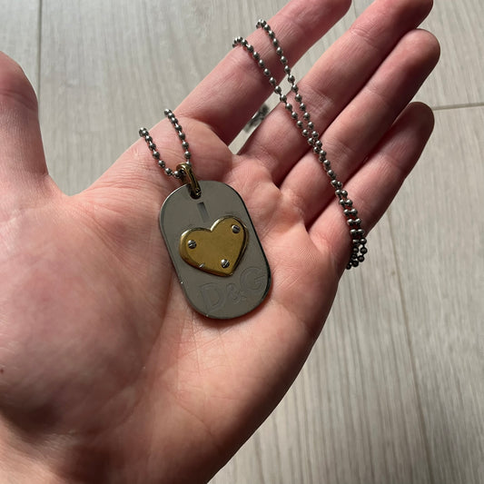 Dolce & Gabbana "I ❤️ D&G" Gold Dog Tag Necklace with a silver stainless steel ball chain, featuring a dog tag engraved with a light "I", a gold metal heart with 3 visible screws, and "D&G" text below, forming the "I ❤️ D&G" design. A playful and collectible vintage piece.