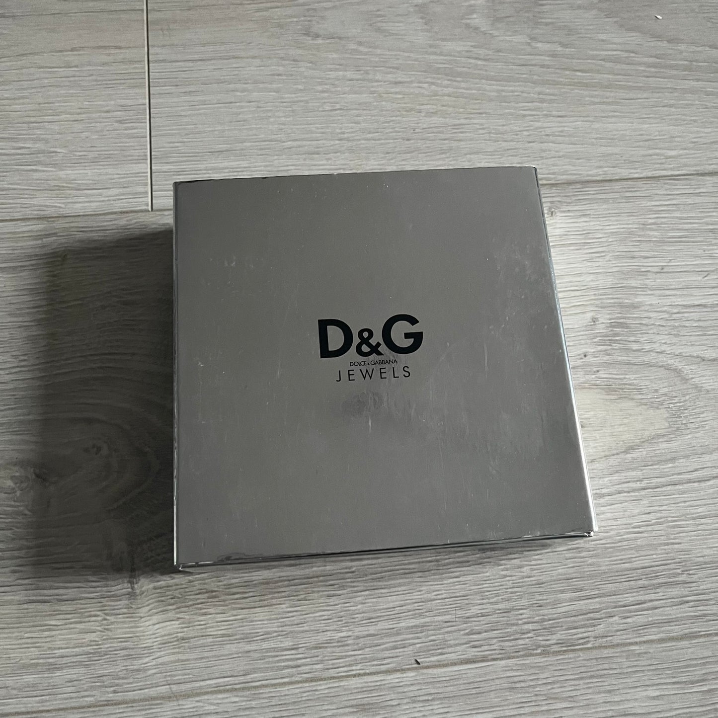 Dolce & Gabbana Pearl Brown Rosary Necklace from the 2000s era. The necklace features a silver-tone metal cross with a D&G logo, connected via a black leather link to a metal chain with alternating brown and yellow pearl-style beads. Rosary-style construction with mixed materials including metal, leather, and resin pearls. Comes complete with the original box.