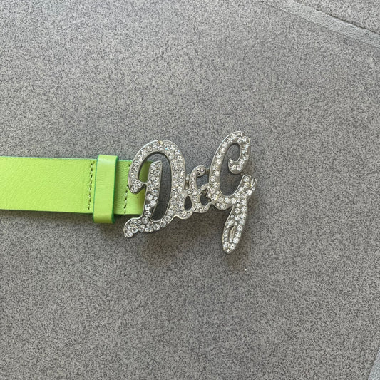 Dolce & Gabbana 2000s Green Crystal Buckle Belt features a lime green leather strap with a stainless steel D&G logo buckle. The buckle has a decorative italic-style font and is fully covered with crystal/rhinestone detailing on the front. Made in Italy.