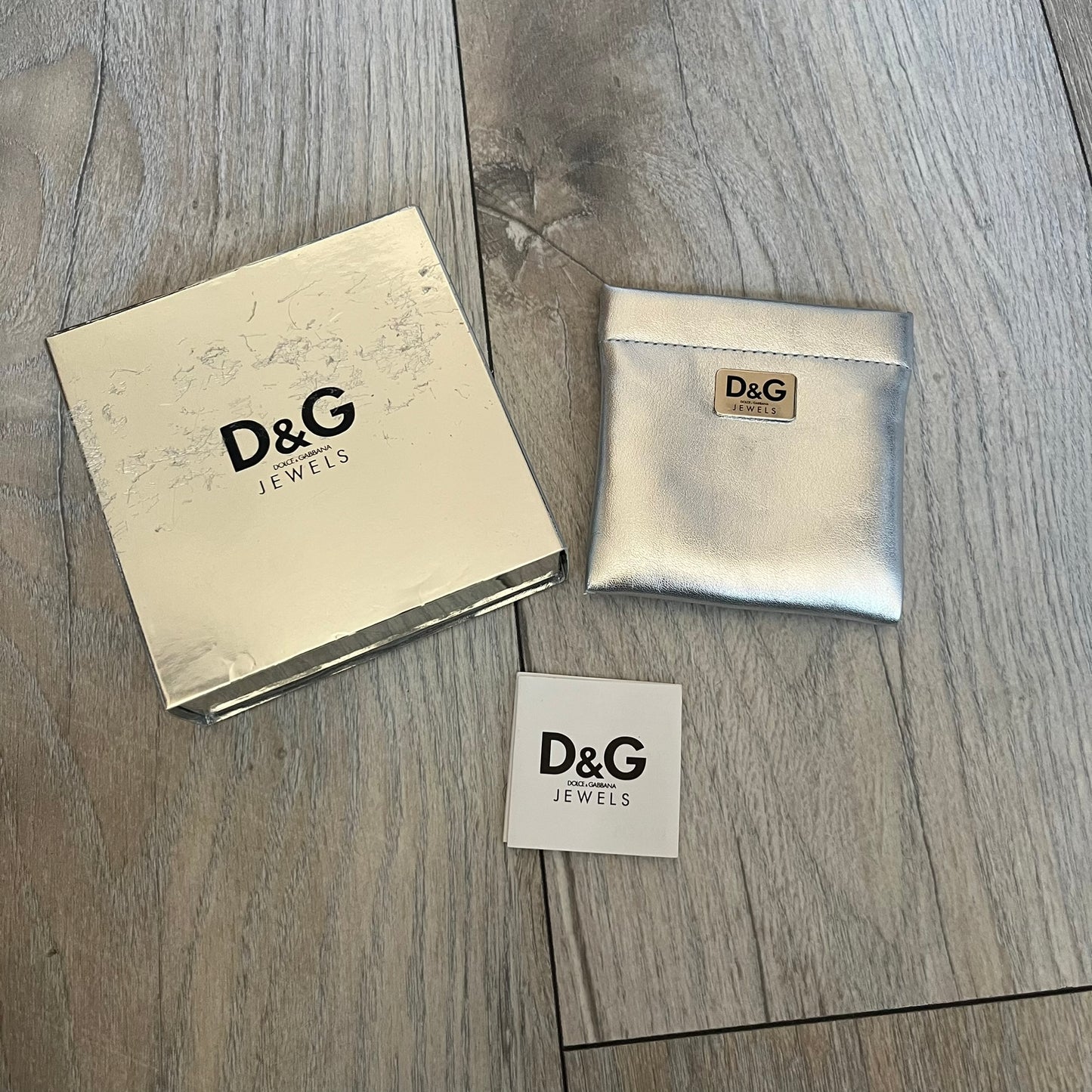 Dolce & Gabbana 2000’s Stainless Steel Bracelet DJ0552 is a thick bracelet made from stainless steel featuring large Cuban-style links. The center includes a plaque with a small engraved D&G logo, while the clasp is also marked with Dolce & Gabbana branding. The piece is referenced as DJ0552 and comes with the original box and dustbag.