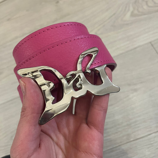 Dolce & Gabbana 2008 Butterfly Buckle Pink Leather Belt from the AW2008 collection. Crafted from smooth pink leather with visible edge stitching, this belt features a big silver-tone D&G logo buckle shaped in a butterfly-style form. The buckle has a polished metal finish, while the belt itself is made from 100% leather and retains a clean, structured profile. An original seasonal accessory from Dolce & Gabbana’s AW2008 season.