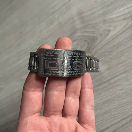 Dolce & Gabbana Warning Stainless Steel Bracelet. From the Spring/Summer 2006 collection, this bracelet features a polished stainless steel design with a clip closure. The front plate displays “Warning Special Access Required” alongside D&G Dolce & Gabbana branding.