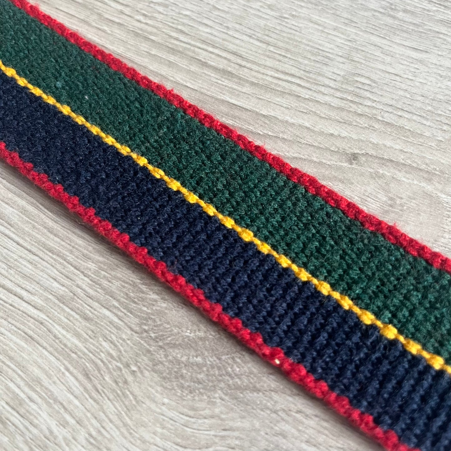 Dolce & Gabbana "Campus Since 1994" Material Belt features a multicolor cotton webbing strap in red, navy, green, and yellow with leather-tipped ends. The statement metal buckle displays a crest design with D&G branding, a central “Campus Since 1994” motif, and multiple national flags. A sporty accessory that combines vintage with luxury detail.