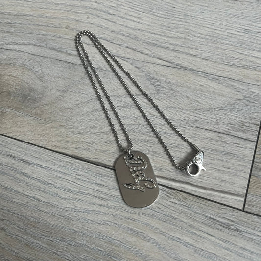 The Dolce & Gabbana Crystal Logo Dog Tag Necklace features a silver-tone ball chain with two pendants: a plain dog tag and a cutout D&G logo adorned with crystals. It has a large clasp engraved with D&G and model markings, from the 2000s.
