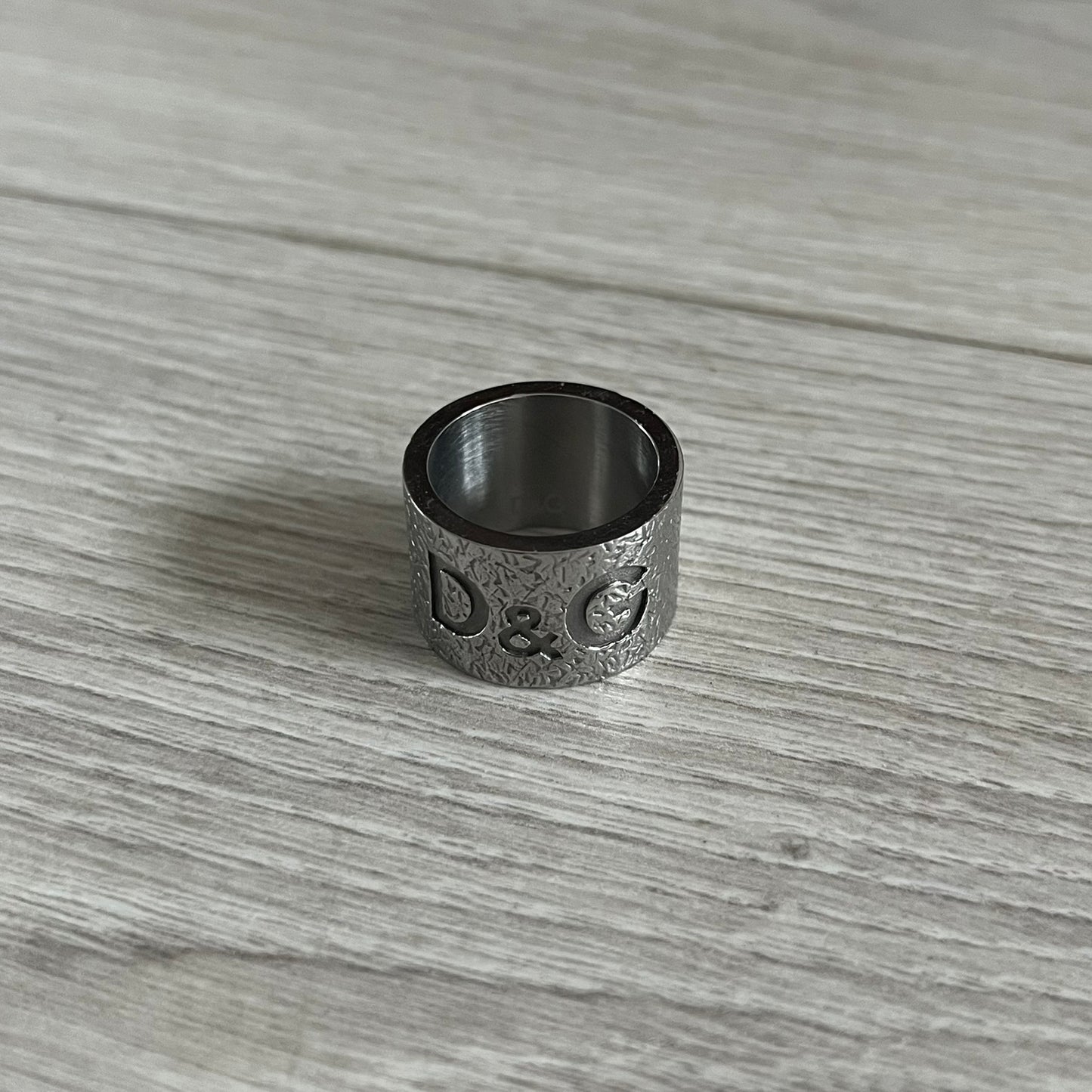Silver ring with engraved text on a wooden surface
