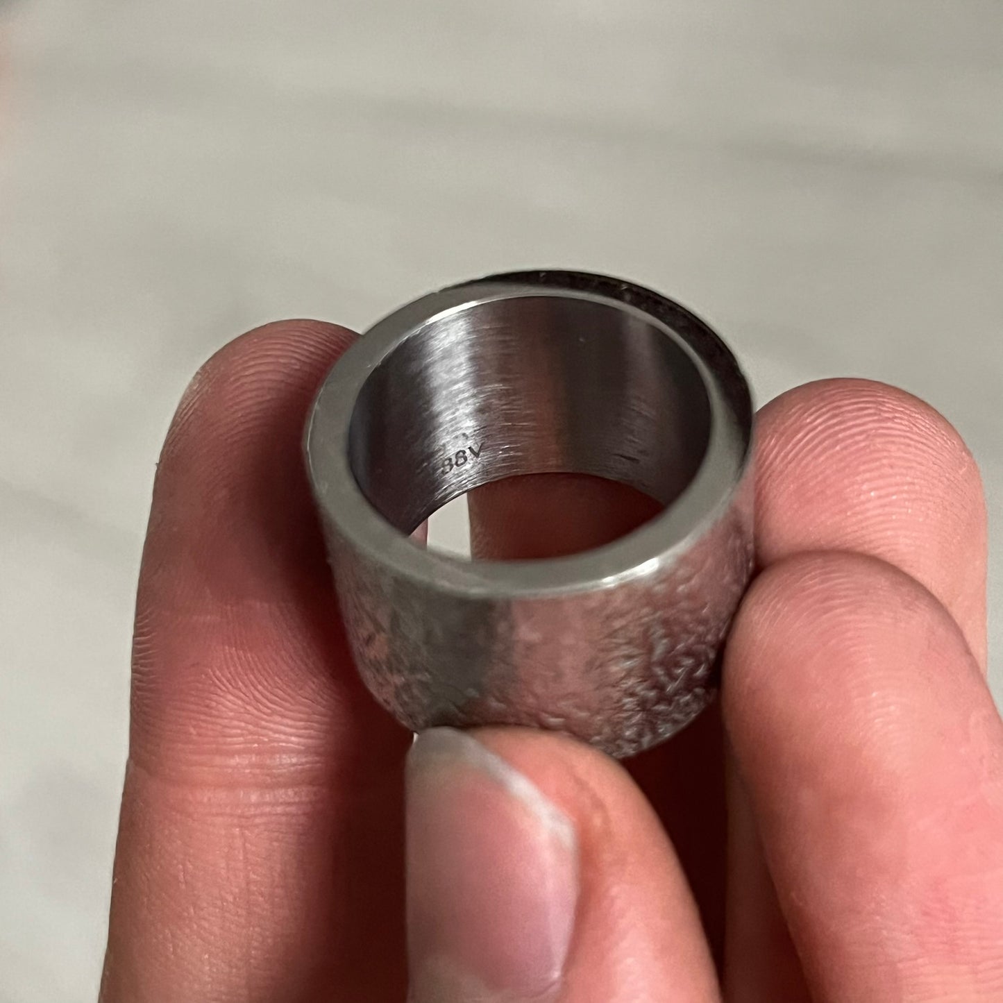 Metallic ring held between fingers against a neutral background