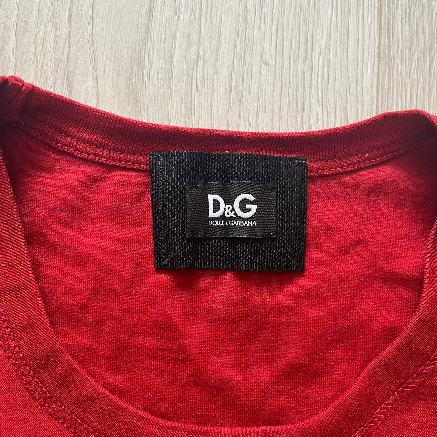 Dolce & Gabbana Fall 2011 tee in vibrant red featuring a simple “Drink Coca-Cola” logo on the chest. Designed with an inside-out stitching aesthetic and a subtle back logo under the collar. A unique, collectible tee that merges casual branding with high-fashion flair.