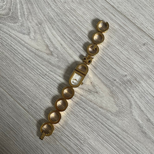 Gold watch with a chain-like design on a gray wooden surface