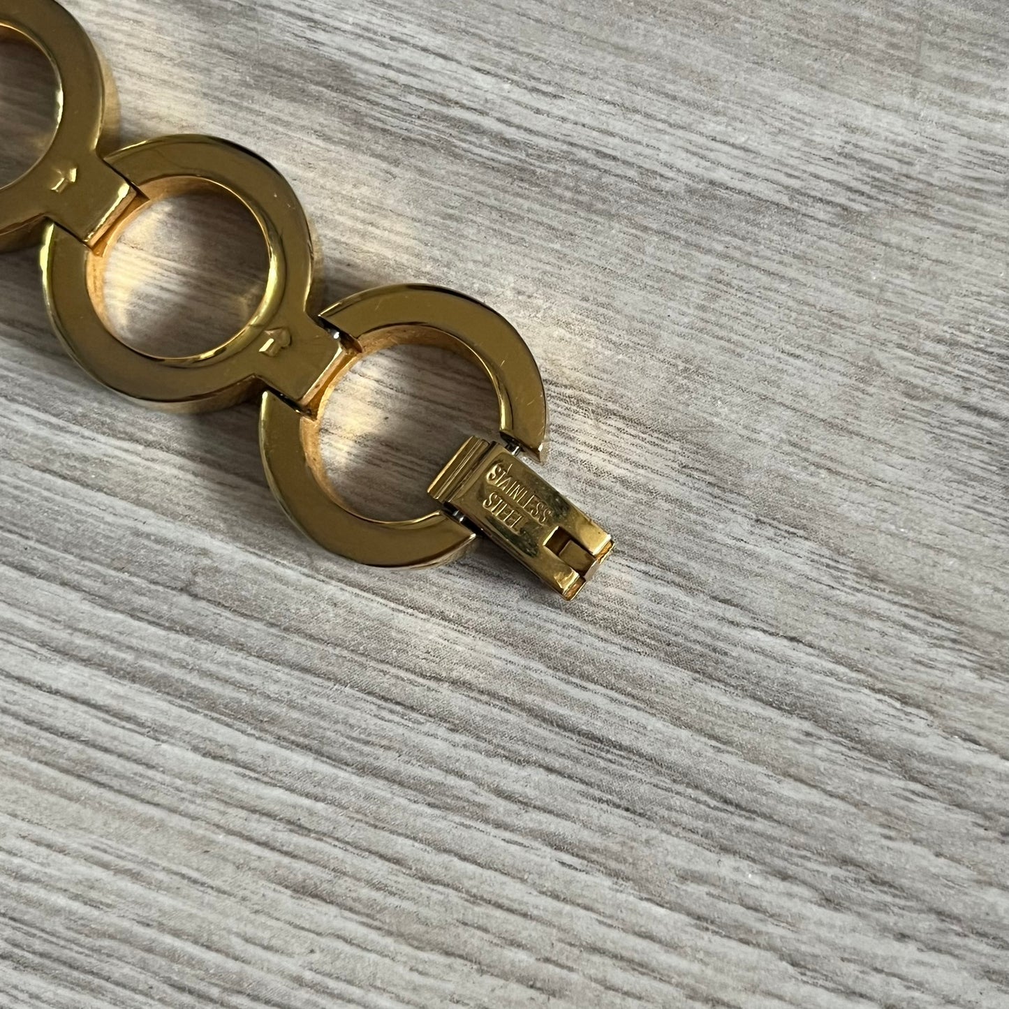 Gold bracelet with a key charm on a gray textured surface