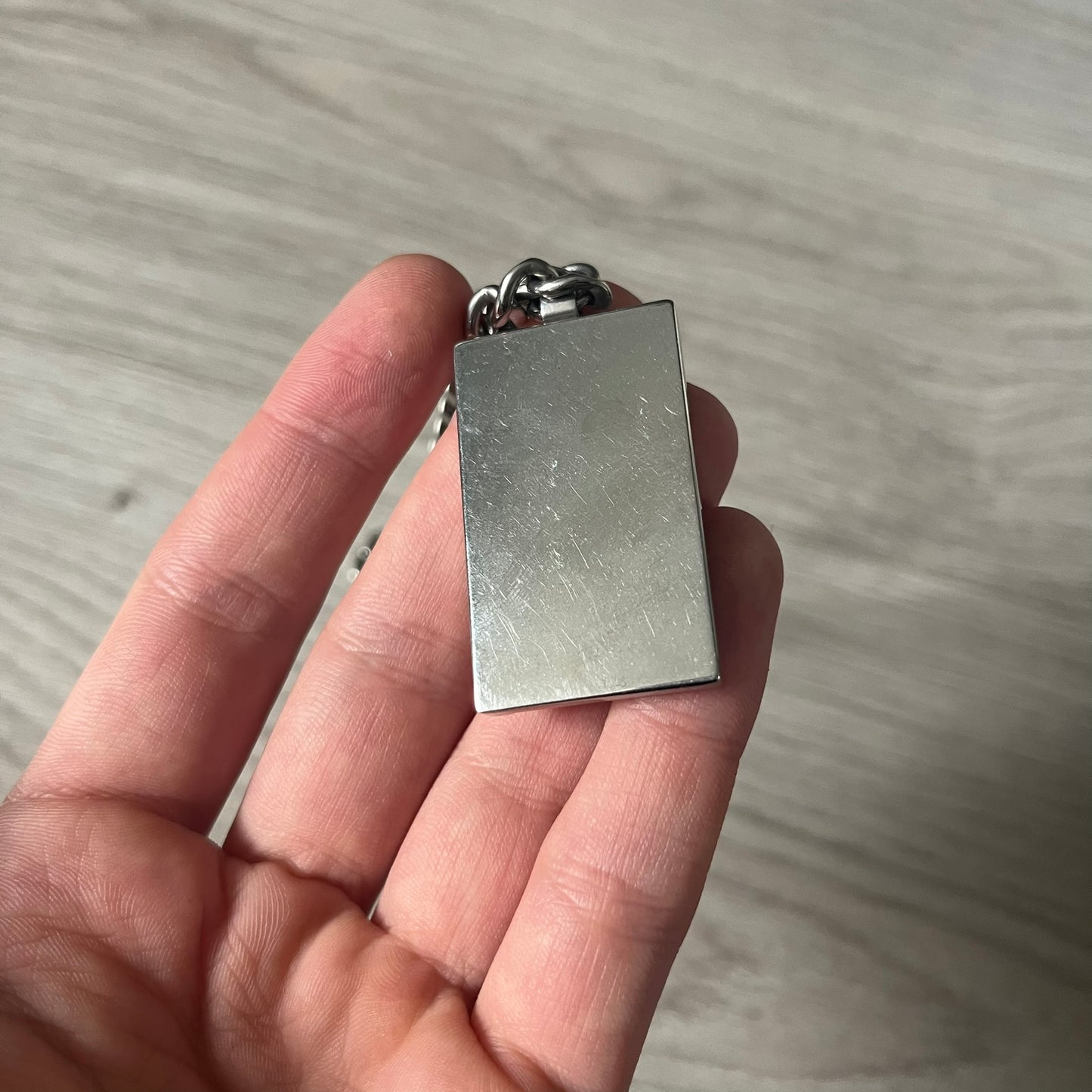 D&G DJ0564 Pendant Necklace showcases a large silver curb chain paired with a rectangular silver frame pendant. Inside, black leather embossed with the D&G logo adds contrast and sophistication. A striking blend of luxury leather and stainless steel craftsmanship.