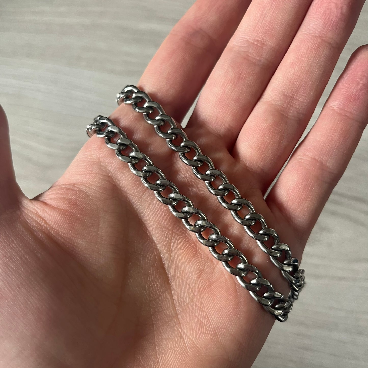 D&G DJ0564 Pendant Necklace showcases a large silver curb chain paired with a rectangular silver frame pendant. Inside, black leather embossed with the D&G logo adds contrast and sophistication. A striking blend of luxury leather and stainless steel craftsmanship.