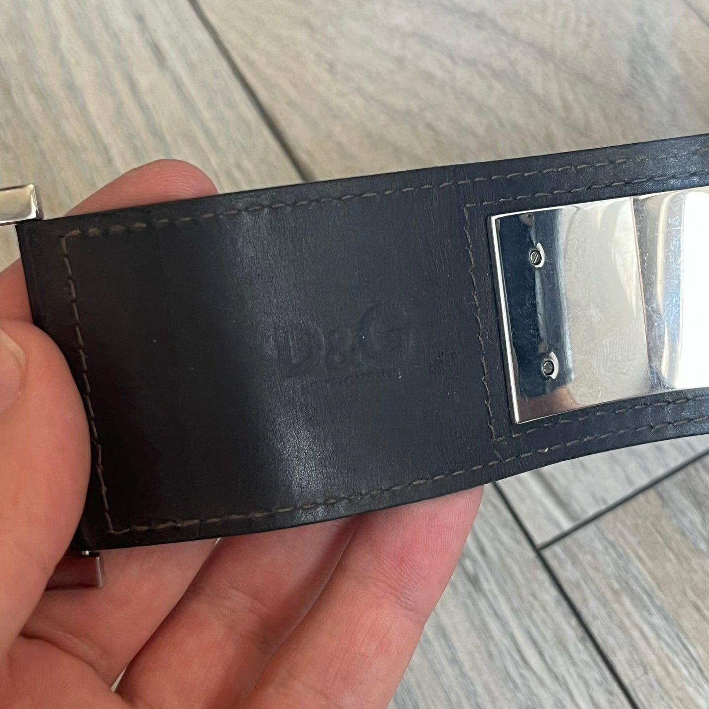 Dolce & Gabbana Logo Leather Bracelet is a leather bracelet made in Italy. It features an adjustable closure and a large stainless steel plaque on the front. The plaque is engraved with the D&G logo and Dolce & Gabbana text. Silver-tone hardware is used throughout the bracelet.
