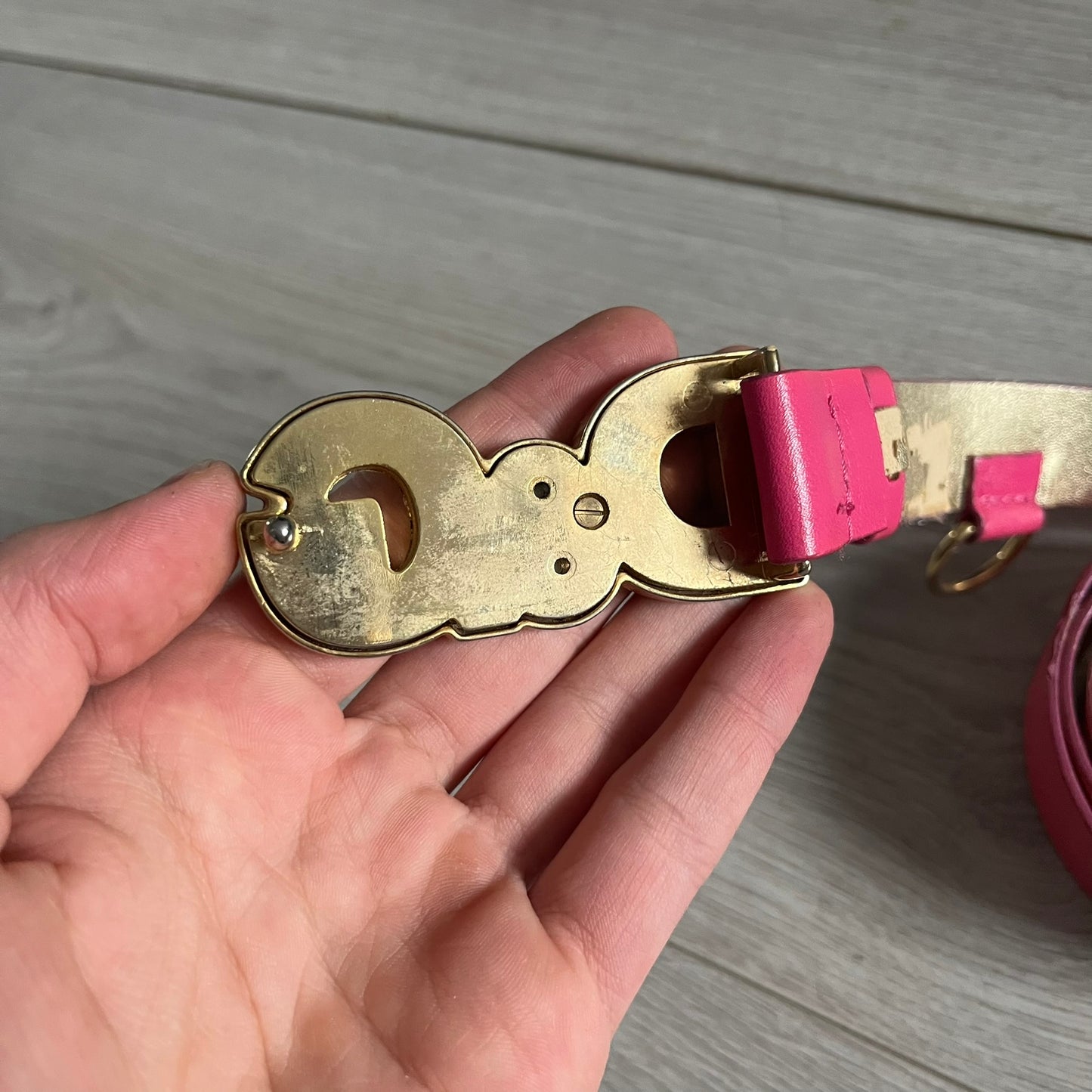 This Dolce & Gabbana Belt combines a slim pink design with a statement D&G buckle framed in gold and accented by visible screws. The inner side of the belt features a gold finish, highlighting the brand’s attention to material contrast. A classic Italian accessory crafted with detailed hardware.