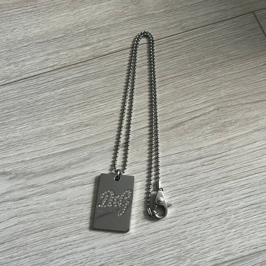 Dolce & Gabbana Rhinestones Dog Tag Necklace DJ0704 crafted from polished stainless steel. Features a rectangular pendant with the iconic D&G logo detailed in rhinestones, and “Dolce & Gabbana” engraved subtly below. Secured with a lobster clasp and finished with a durable ball chain.