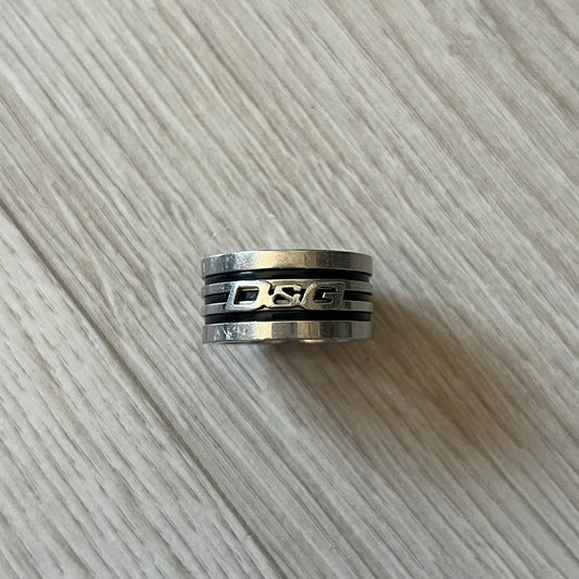 Dolce & Gabbana stainless steel ring DJ0709 in silver, featuring three subtle black engraved stripes encircling the band. The D&G logo is displayed in polished silver on top, creating a nice contrast with the dark detailing.