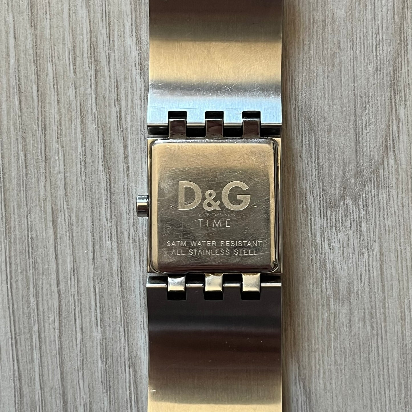 Dolce & Gabbana white analog watch with a silver bracelet featuring white leather-like panels. The case seamlessly aligns with the width of the bracelet for a sleek, integrated look. A refined statement piece blending luxury design with modern elegance.