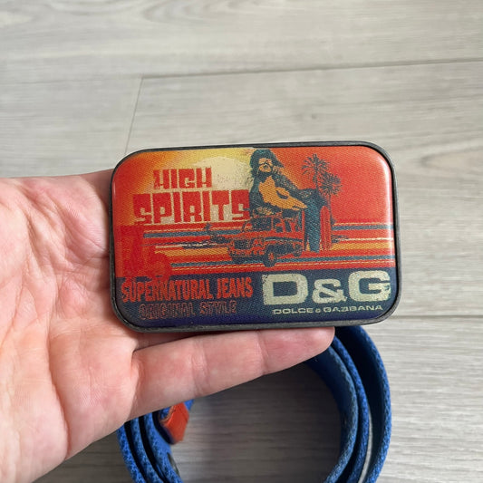 Dolce & Gabbana “High Spirits” Fabric Belt in blue with a brown central stripe and enamel-finished metal buckle. The buckle features vintage iconography and “High Spirits” lettering in vivid orange/red and navy tones. A rare 2000s-era Dolce & Gabbana belt showcasing the brand’s early denim aesthetic.