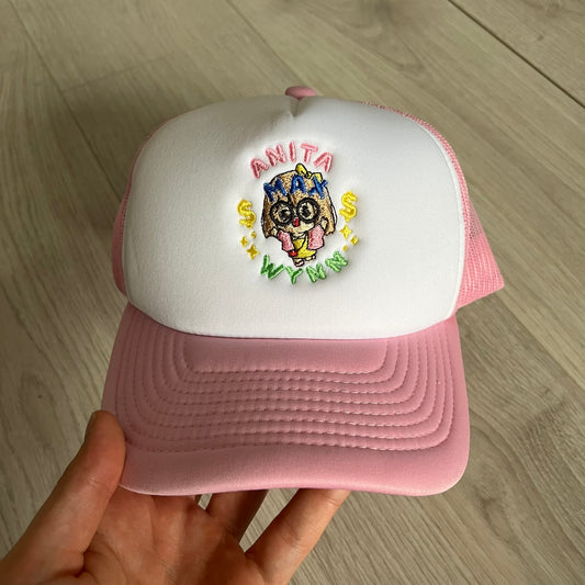 The Drake Anita Max Wynn Hat Punk is a trucker hat that pays tribute to hip-hop artist Drake’s alter ego, Anita Max Wynn. Pink sides and cap, white front.
The hat was inspired by Drake’s love of gambling and his need to get a "max win." The details include a collection of graphics on the front, such as a woman with an oversized head and a pink jacket, two yellow dollar signs, "ANITA" in pink, "MAX" in Blue, and " WYNN" in green. The hat features an construction with a mesh back. A traditional snapback provi