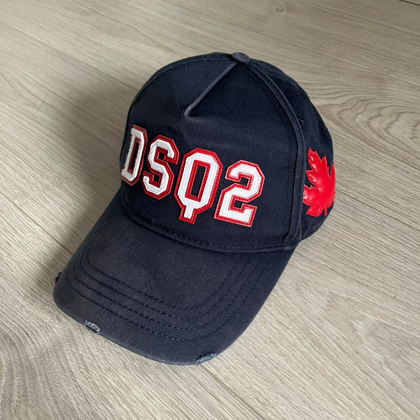 Black cap with 'DSQ2' and red maple leaf logo on a wooden surface