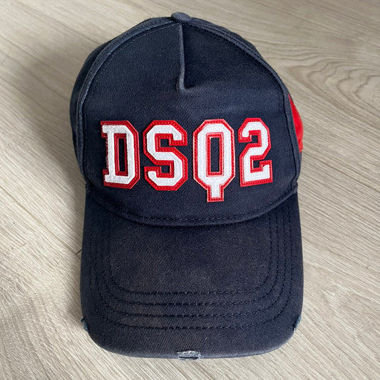 Navy blue cap with 'DSQ2' in red and white on a wooden surface