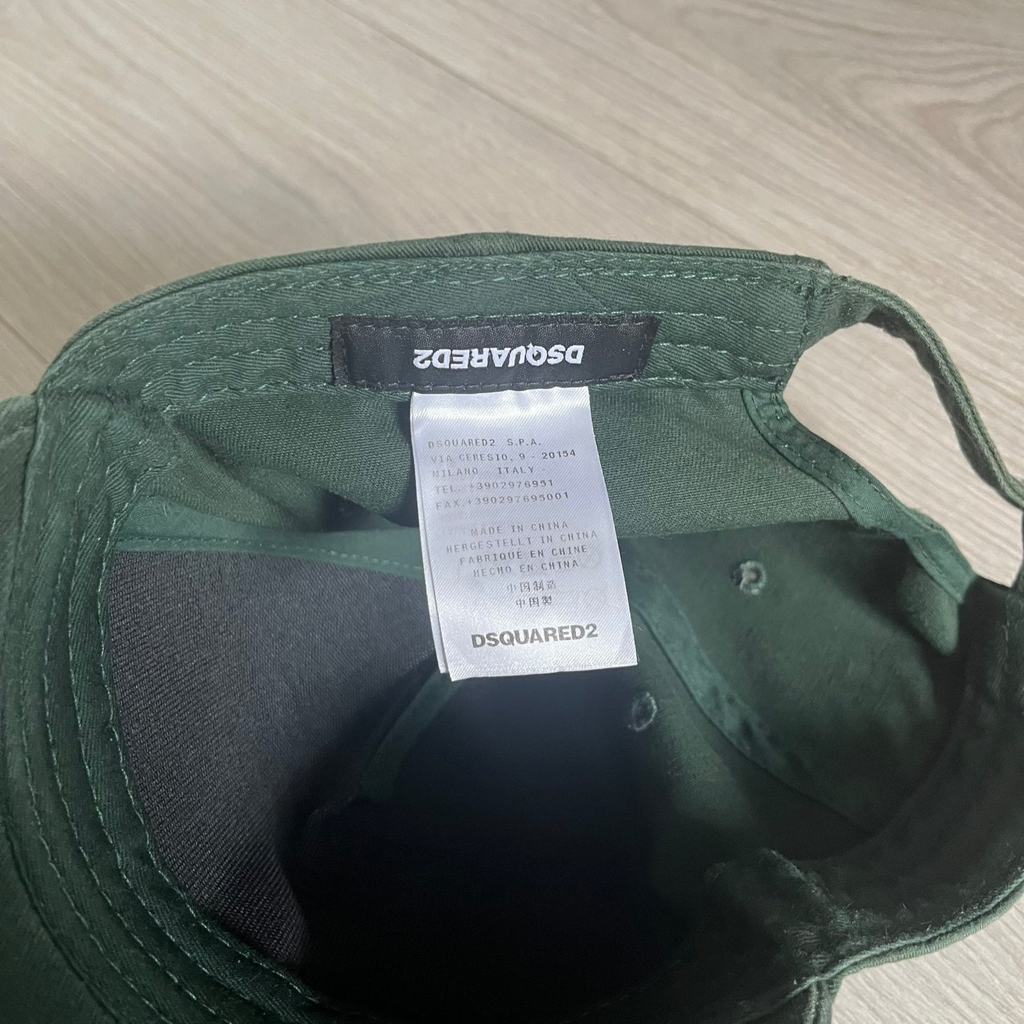 Green cap with Dsquared2 label on a light wooden surface