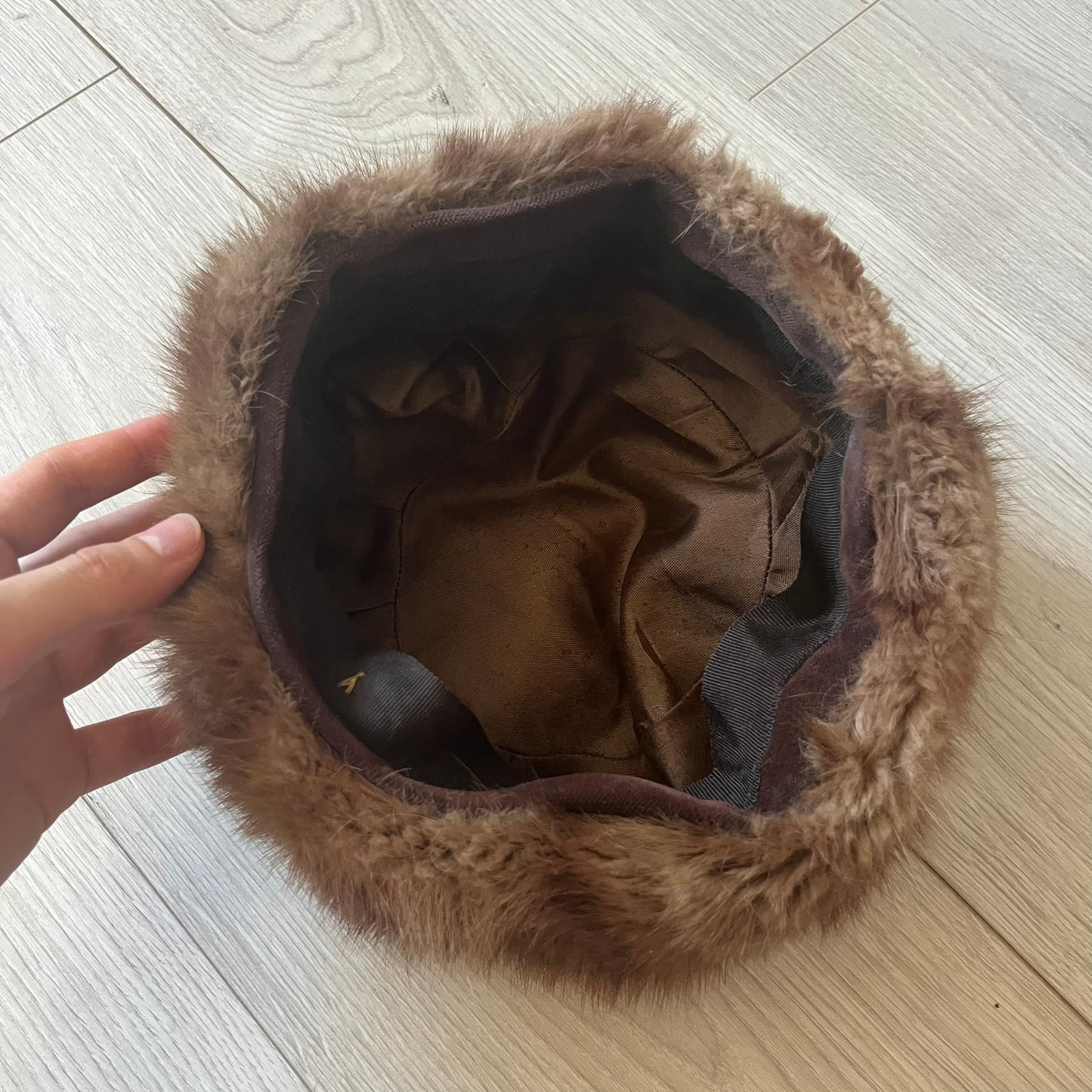 Brown fur winter hat in a compact beret-style shape, resembling a classic pillbox design. Soft and cozy, it provides warmth while maintaining a sleek, minimalist silhouette. A subtle yet stylish accessory for cold-weather wear.