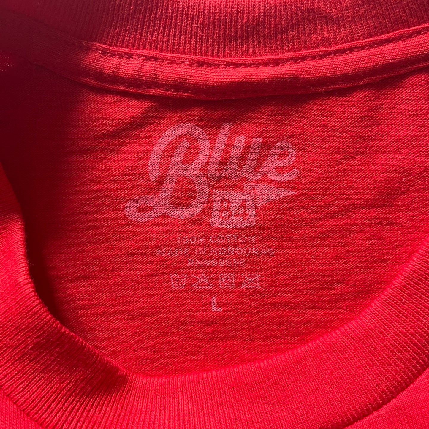 Close-up of a red garment with 'Blue' branding on the label.