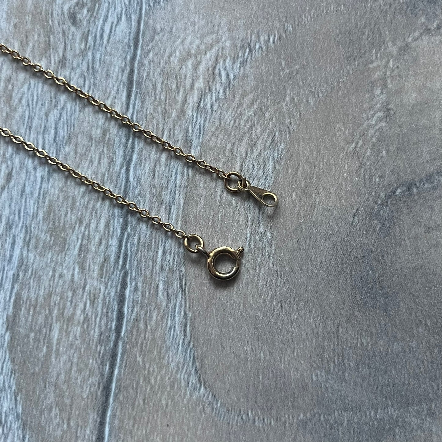 The Givenchy Gold-Tone Vintage Pendant Necklace features a thin gold-tone chain with a central “G” logo pendant embellished with rhinestones. The foldover clasp is stamped Givenchy Paris New York, completing this vintage piece.